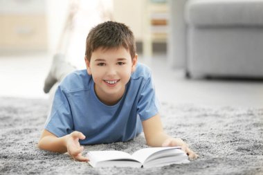 Kitaplı çocuk evde yerde yatıyor.