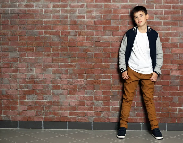 レンガの壁の近くに立ってかわいい男の子 — ストック写真