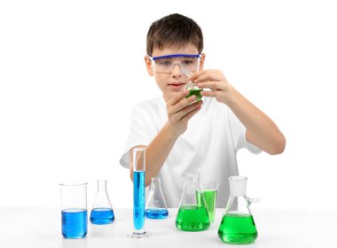 Zeki küçük çocuk beyaz üzerinde izole edilmiş kimyasal deneyler yapıyor.