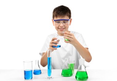 Zeki küçük çocuk beyaz üzerinde izole edilmiş kimyasal deneyler yapıyor.