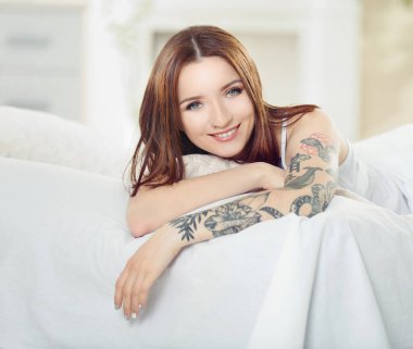 Yatağında dövmesi olan çekici bir kadın.