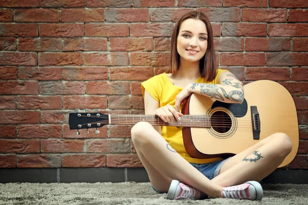 Vrouw Met Tatoeage Gitaar Zittend Achtergrond Bakstenen Achtergrond — Stockfoto