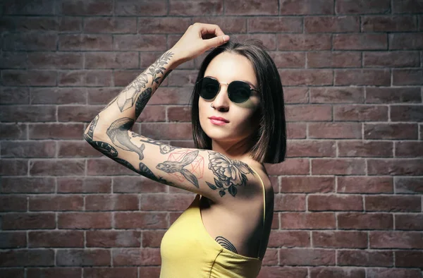 Mulher Bonita Com Tatuagem Usando Óculos Sol Posando Fundo Parede — Fotografia de Stock