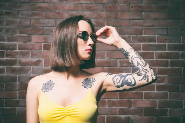 Mulher Bonita Com Tatuagem Usando Óculos Sol Posando Fundo Parede — Fotografia de Stock