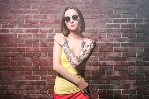 Mulher Bonita Com Tatuagem Usando Óculos Sol Posando Fundo Parede — Fotografia de Stock