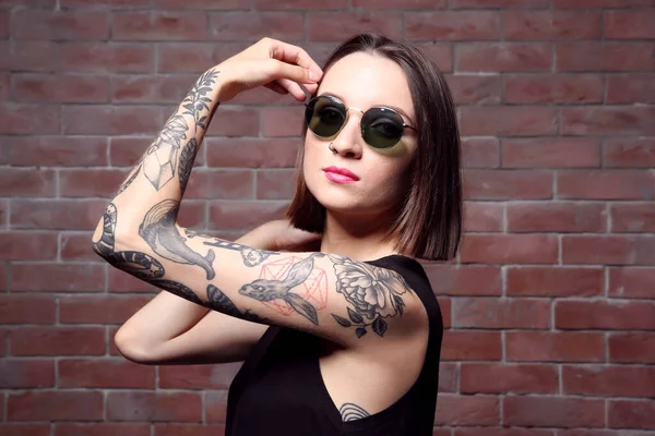 Mulher Bonita Com Tatuagem Usando Óculos Sol Posando Fundo Parede — Fotografia de Stock