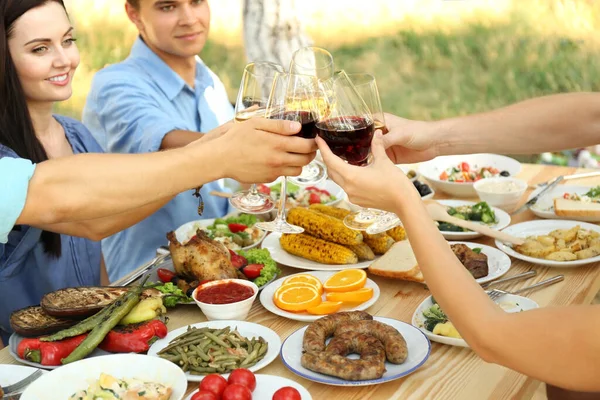 Friends cheering with glasses of wine on picnic