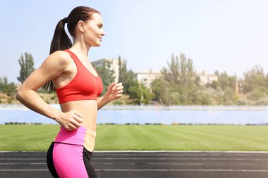 Stadyumda koşan güzel bir genç kadın.