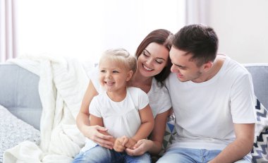 Mutlu aile ve kızı kanepede.