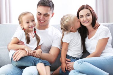 Mutlu ebeveynler ve kızları kanepede.