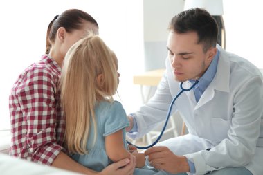 Erkek çocuk doktoru küçük kızı muayene ediyor.