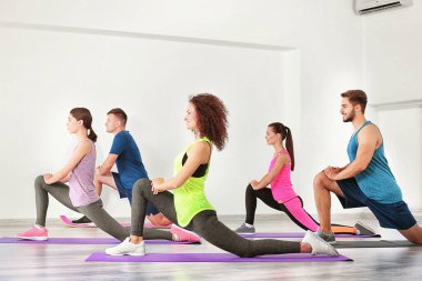Spor salonunda yoga yapan bir grup insan.