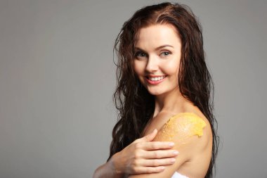 Gri arka planda omuz masajı yapan genç bir kadın.