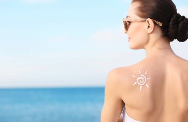 Woman with sun protective lotion in sun shape on shoulder clipart
