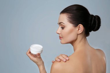 Gri arka planda krema kabı olan güzel genç bir kadın.