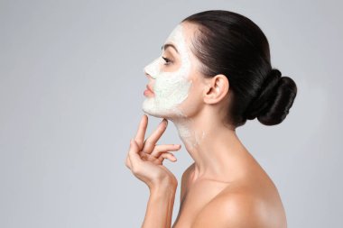 Güzel genç bir kadın yüzüne maske takıyor, yakın plan.