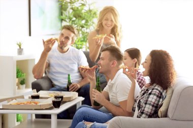 Arkadaşlar ev partisinde lezzetli pizza yiyorlar.