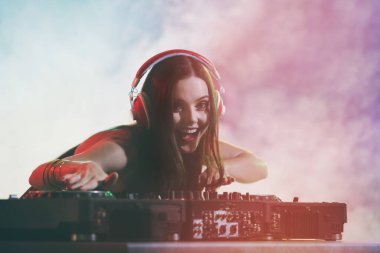 Güzel genç DJ gece kulübünde müzik çalıyor.