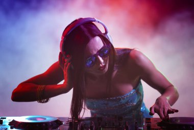 Güzel genç DJ gece kulübünde müzik çalıyor.