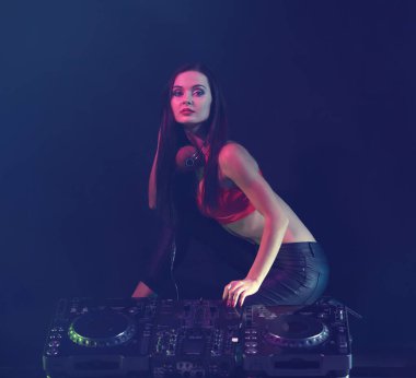 Koyu arkaplanda DJ konsolu olan güzel genç bir kadın.