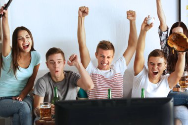 Genç hayranlar TV 'de bira ve atıştırmalıklarla beyzbol maçı izliyor.