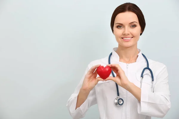 Kobieta Lekarz Stetoskopem Trzymającym Serce Jasnym Tle — Zdjęcie stockowe