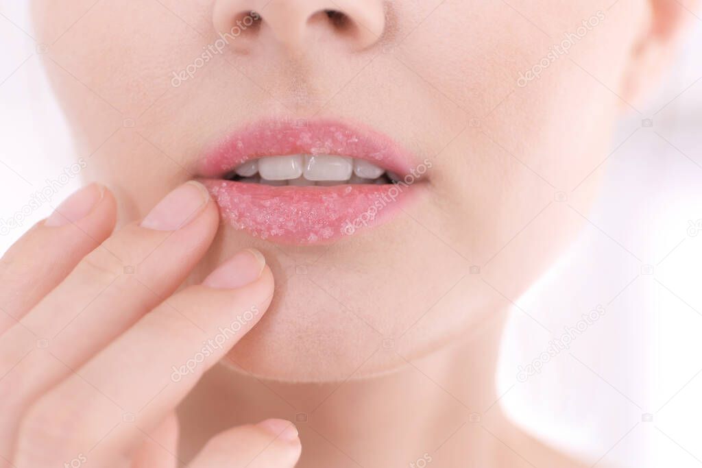 Lips of beautiful young woman covered with sugar scrub