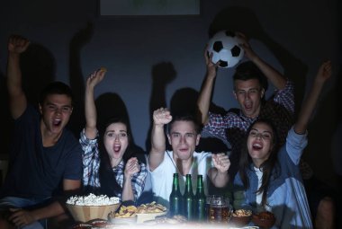 Genç hayranlar akşam geç saatlerde TV 'de bira ve atıştırmalıklarla maç izliyorlar.