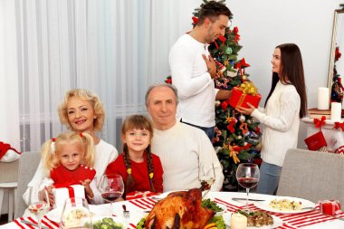 Mutlu aile Noel yemeğini oturma odasında yiyor.