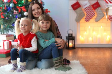 Oturma odasında iki kızı olan güzel kadın Noel için dekore edilmiştir.