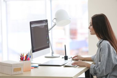 Genç bayan tasarımcı ofiste çalışıyor.