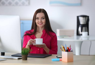 Genç ve güzel tasarımcı ofiste kahve içiyor.