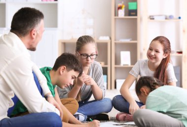 Erkek öğretmen okulda ders veriyor.