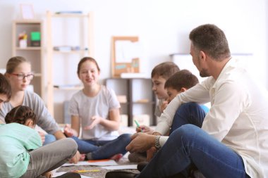 Erkek öğretmen okulda ders veriyor.