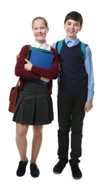 Beyaz arka planda duran okul üniformalı hoş bir çocuk ve kız.