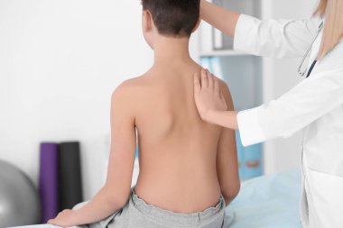 Yanlış duruş konsepti. Fizyoterapist çocuğun sırtını muayene edip düzeltiyor.