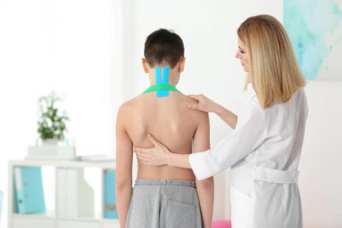 Yanlış duruş konsepti. Fizyoterapist çocuğun sırtını muayene edip düzeltiyor.