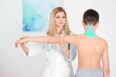 Yanlış duruş konsepti. Fizyoterapist çocuğun sırtını muayene edip düzeltiyor.