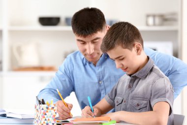 Baba ve oğul ev ödevlerini evde yapıyorlar.