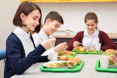 Öğle Yemeği yerken okul kafeteryasında masada oturan çocuk