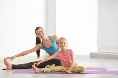 Anne ve kızı içeride egzersiz yapıyor.