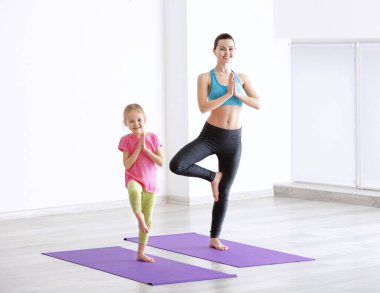 Anne ve kızı içeride egzersiz yapıyor.