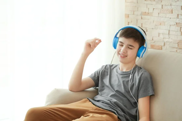 十代の若者たちとともにヘッドフォンで音楽を聴きながら座ってソファに家 — ストック写真
