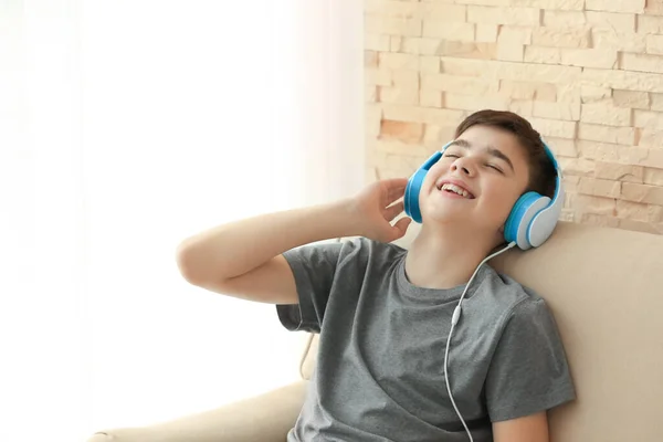 十代の若者たちとともにヘッドフォンで音楽を聴きながら座ってソファに家 — ストック写真