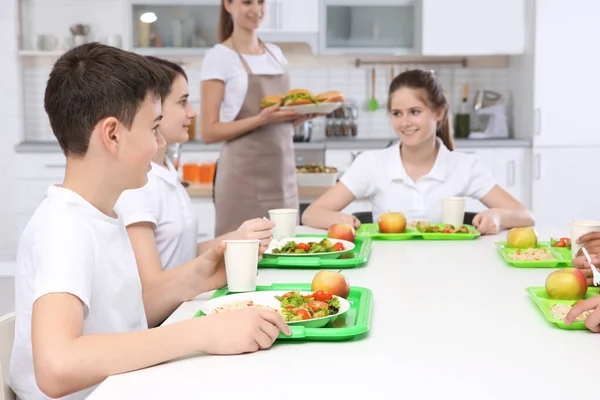 孩子们坐在桌旁在学校食堂吃午饭时 — 图库照片
