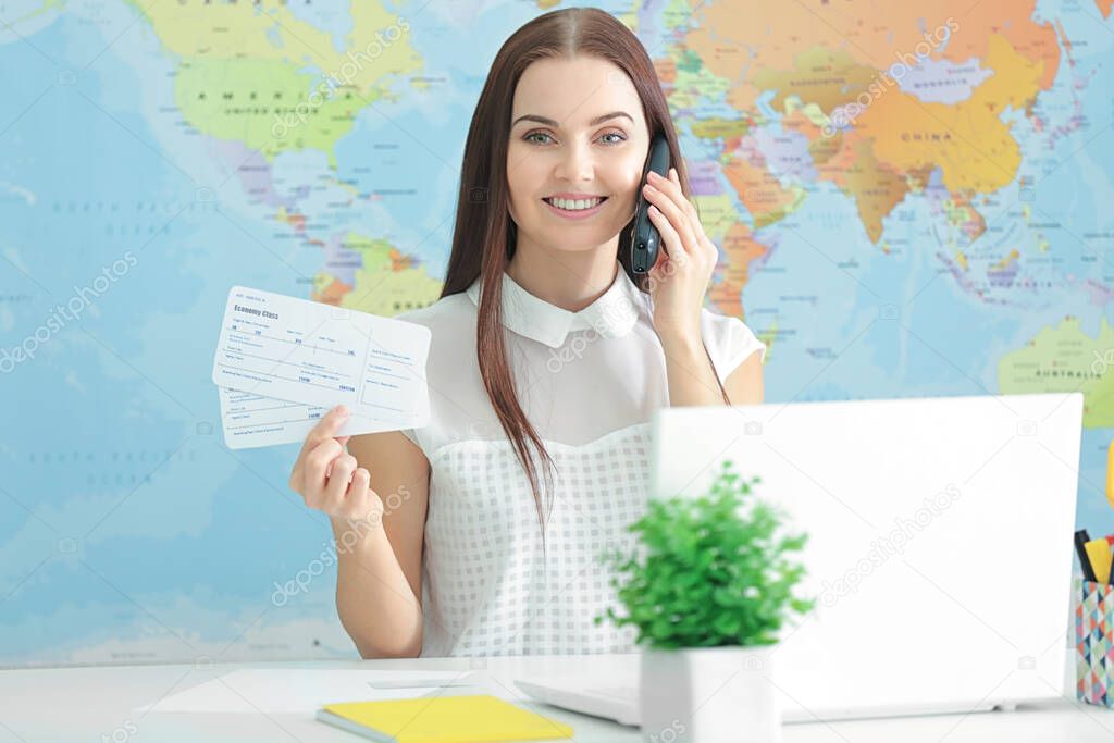 Travel concept. Beautiful woman talking by mobile phone sitting at workplace on map background