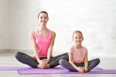 Anne ve kızı içeride egzersiz yapıyor.