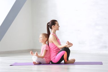 Anne ve kızı içeride egzersiz yapıyor.