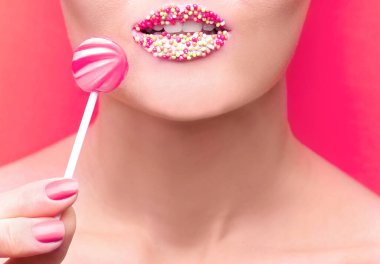 Yaratıcı makyajı olan ve arka planda lolipopu olan güzel bir genç kadın.