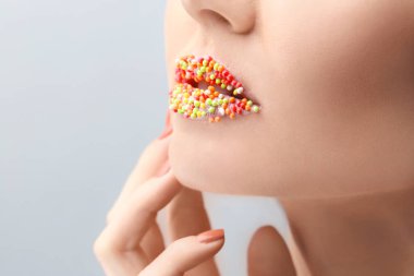 Işıklı arka planda yaratıcı makyajı olan güzel genç bir kadın.